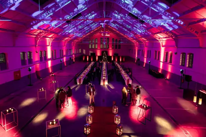 Grande halle éclairée en rose et violet avec les tables du banquet